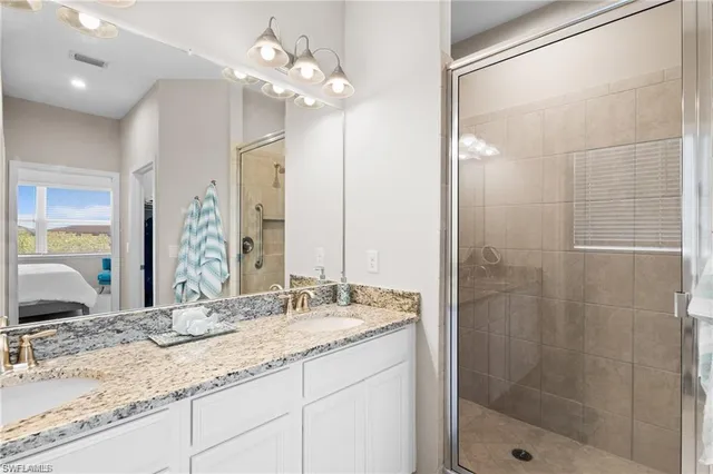 a bathroom with a granite countertop sink a large mirror and shower