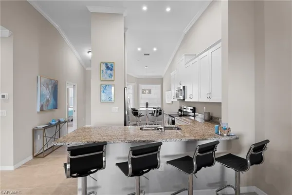 a kitchen with stainless steel appliances kitchen island granite countertop a dining table chairs and white cabinets