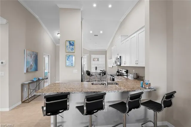 a kitchen with stainless steel appliances kitchen island granite countertop a dining table chairs and white cabinets
