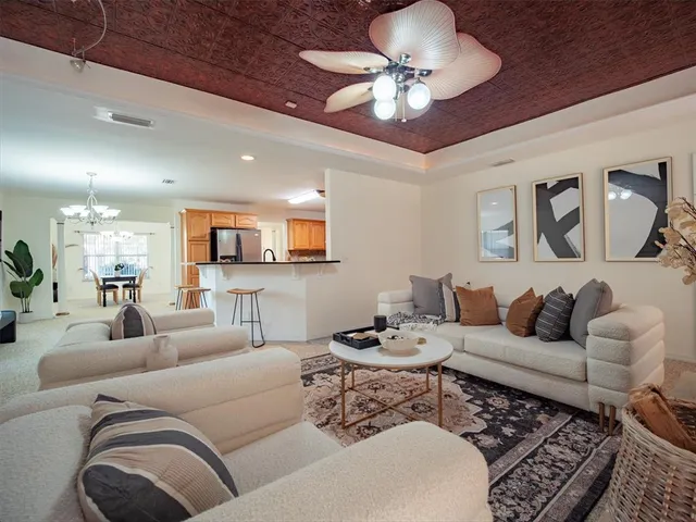 a living room with furniture kitchen view and a chandelier