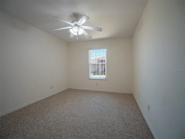 an empty room with a ceiling fan and a window