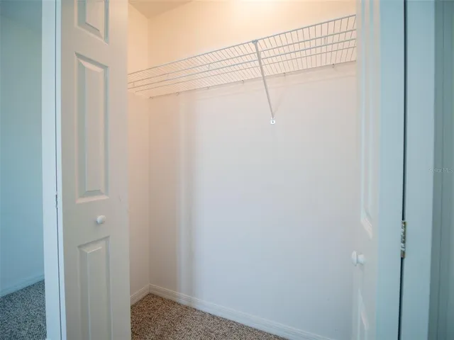 an empty room with a chandelier fan and windows