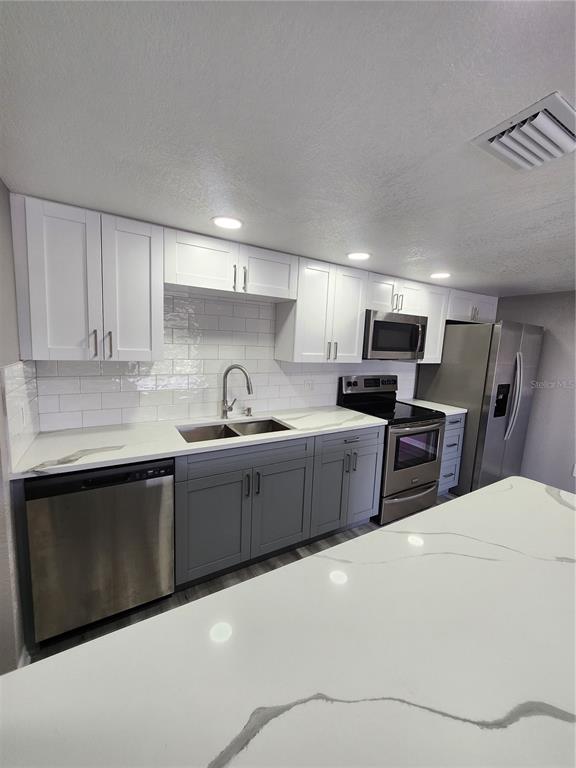 5541 Bay Boulevard, Unit 403 Port Richey, FL 34668 - Photo 2 of 24 a kitchen with stainless steel appliances a sink dishwasher a stove a refrigerator with grey cabinets