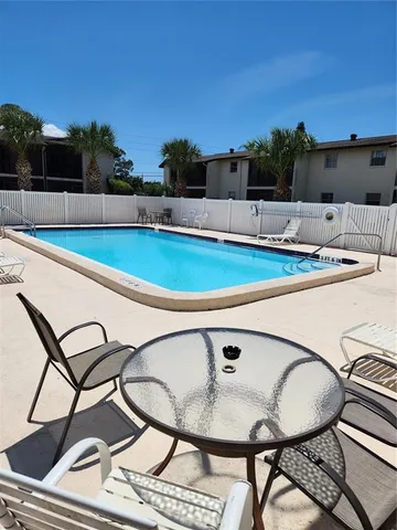 a view of a swimming pool with a lawn chairs and a fire pit