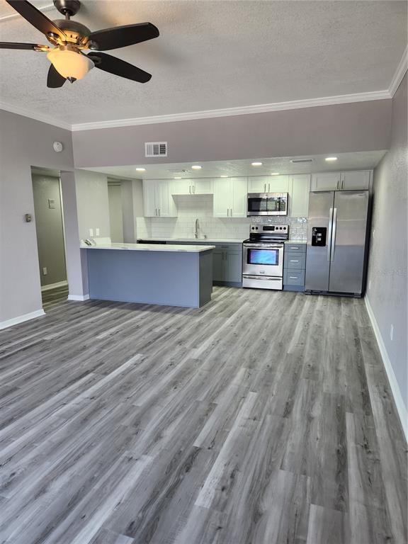 5541 Bay Boulevard, Unit 403 Port Richey, FL 34668 - Photo 3 of 24 a open kitchen with stainless steel appliances kitchen island granite countertop a stove a sink and a refrigerator