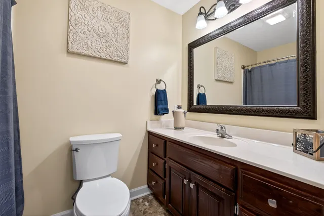a bathroom with a granite countertop sink a toilet and a mirror
