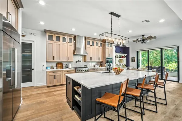 a kitchen with stainless steel appliances granite countertop a stove top oven a sink dishwasher and a dining table with wooden floor