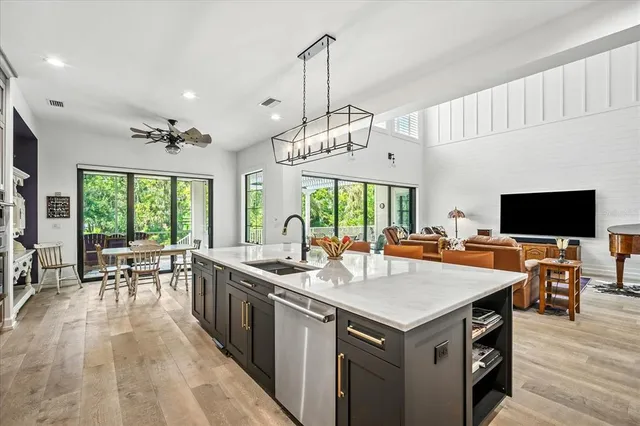 a kitchen with stainless steel appliances granite countertop a stove a sink dishwasher and white cabinets with wooden floor next to windows