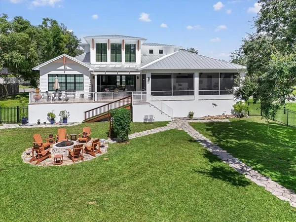 a view of a house with a big yard and potted plants and large trees