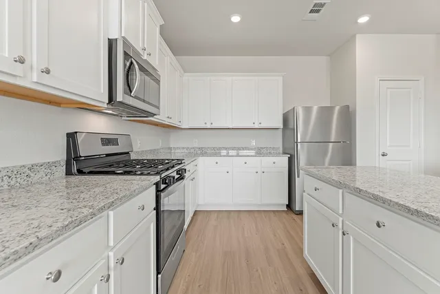 a kitchen with granite countertop a sink stove and refrigerator