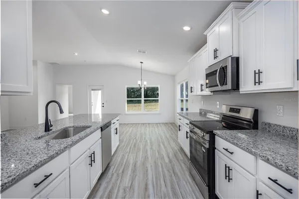 a kitchen with granite countertop a sink stove and cabinets