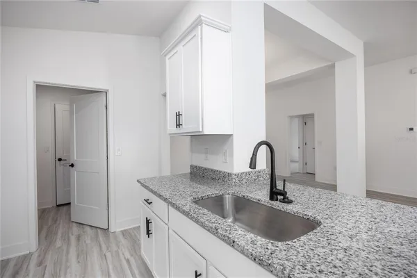 a kitchen with granite countertop a sink and a stove with wooden floors