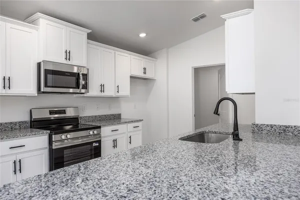a kitchen with stainless steel appliances granite countertop a stove a sink and a microwave