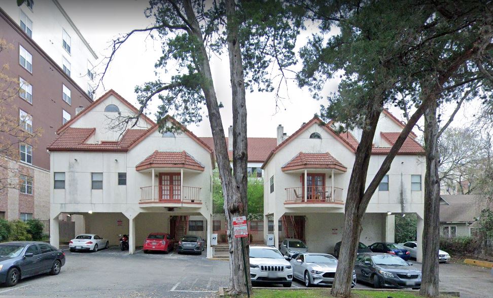 a front view of a building with cars parked