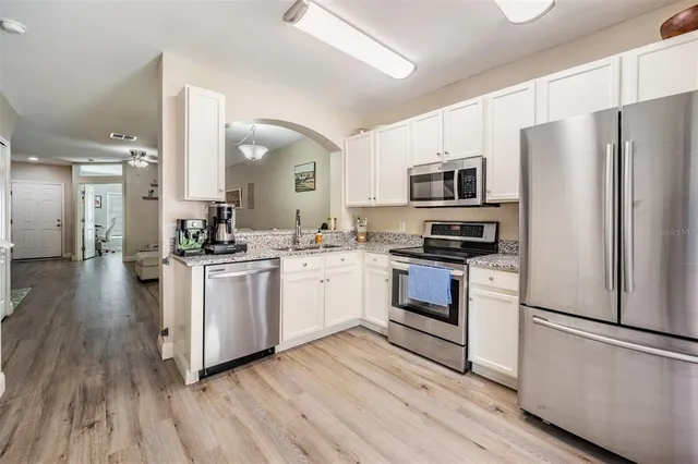 a kitchen with white cabinets stainless steel appliances and wooden floor