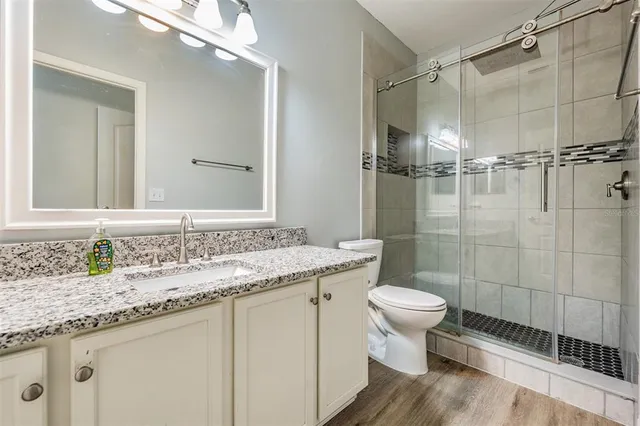 a bathroom with a granite countertop toilet a sink and a mirror