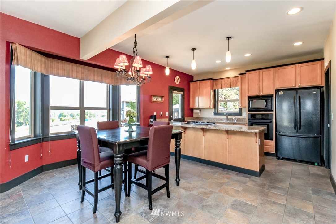 1203 South 3rd Street Renton, WA 98057 - Photo 8 of 40 a kitchen with stainless steel appliances kitchen island granite countertop a table chairs and a refrigerator