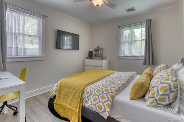 a bedroom with a bed a mirror on dresser and a window