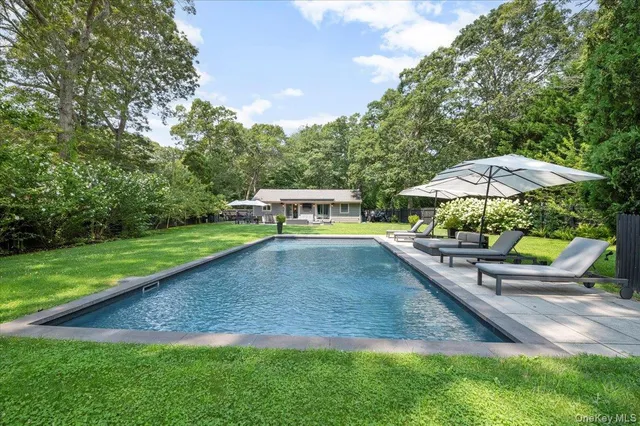 a view of a backyard with chairs and table under an umbrella