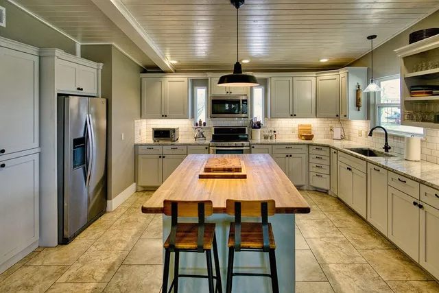a kitchen with stainless steel appliances granite countertop a sink a stove and a refrigerator