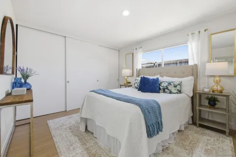 a bedroom with a bed and a potted plant on the dresser