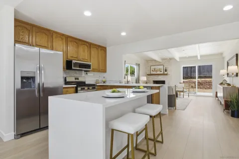 a kitchen with a refrigerator a stove a sink a dining table and chairs