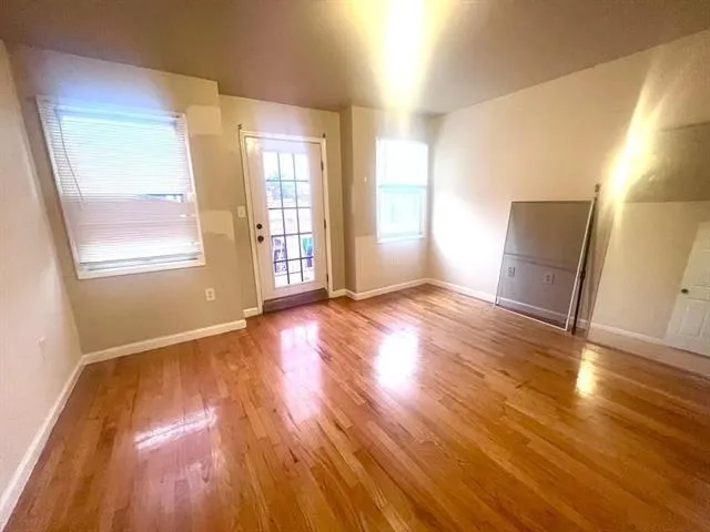 a view of an empty room with wooden floor and a window