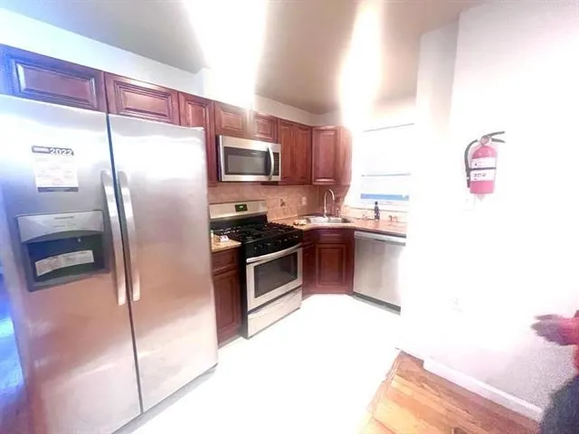a kitchen with kitchen island a counter top space cabinets stainless steel appliances and a window