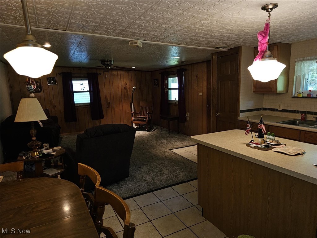 91510 Amos Road Scio, OH 43988 - Photo 7 of 12 Kitchen featuring light countertops, light tile patterned floors, an ornate ceiling, wooden walls, and hanging light fixtures