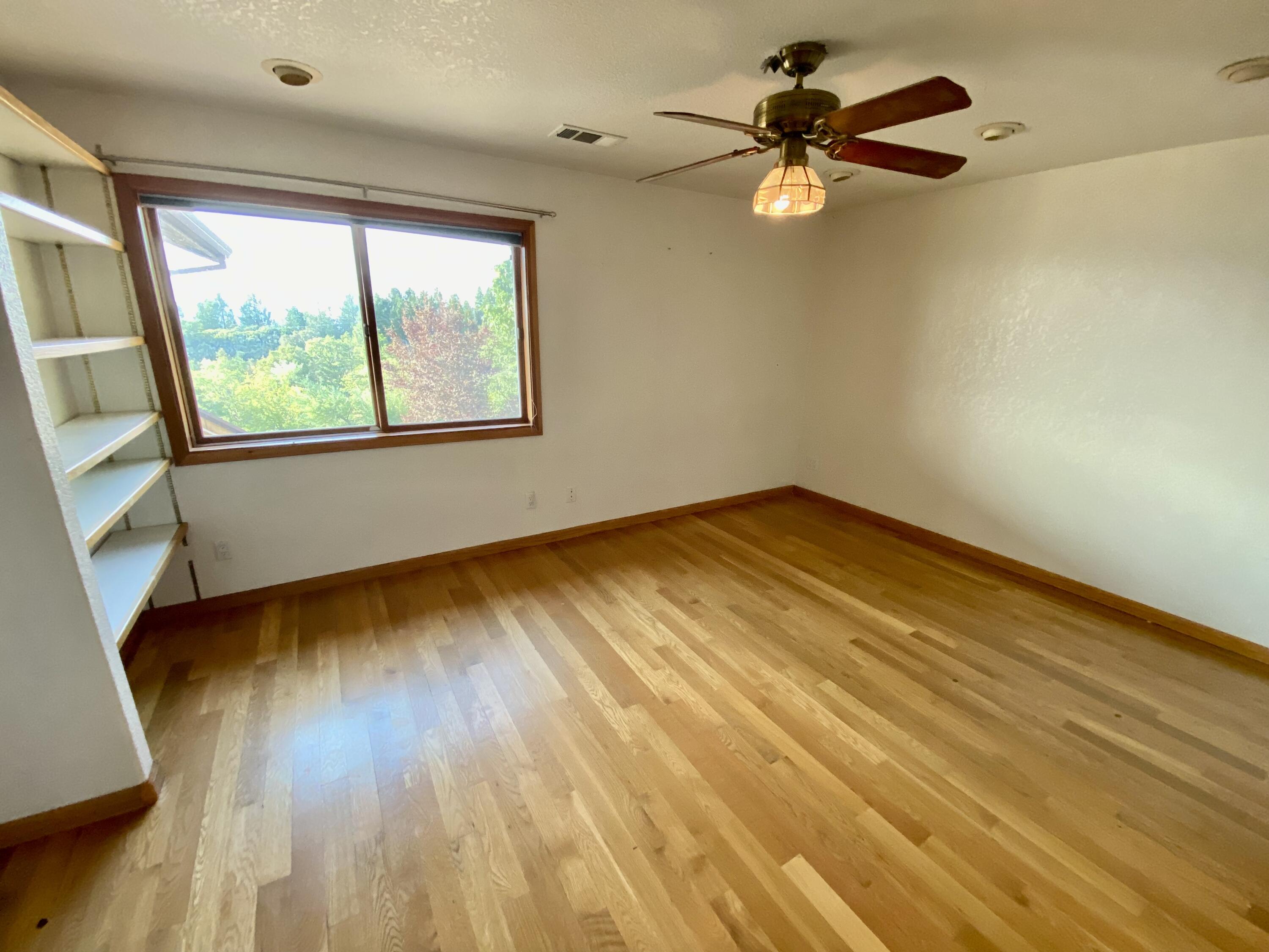 30503 Terry Mill Road Montgomery Creek, CA 96065 - Photo 31 of 75 a view of an empty room with window a ceiling fan and wooden floor