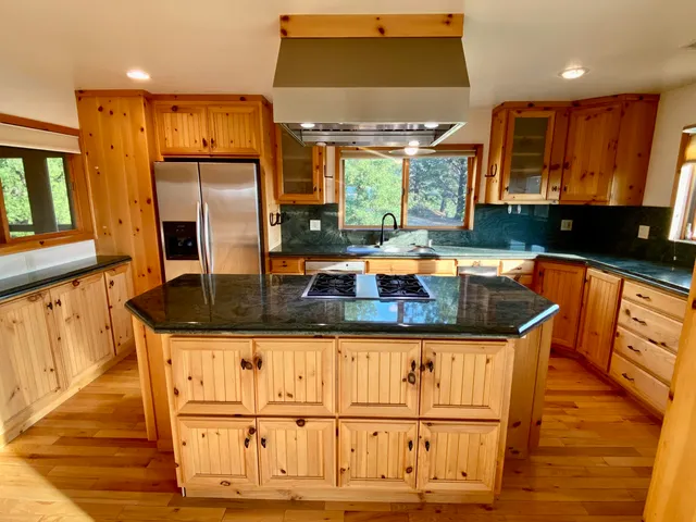 a kitchen with stainless steel appliances granite countertop a sink a stove and a wooden floors