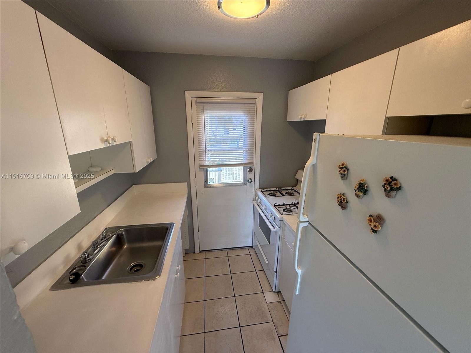 1255 West 49th Place, Unit B201 Hialeah, FL 33012 - Photo 10 of 11 a kitchen with a stove top oven and cabinets