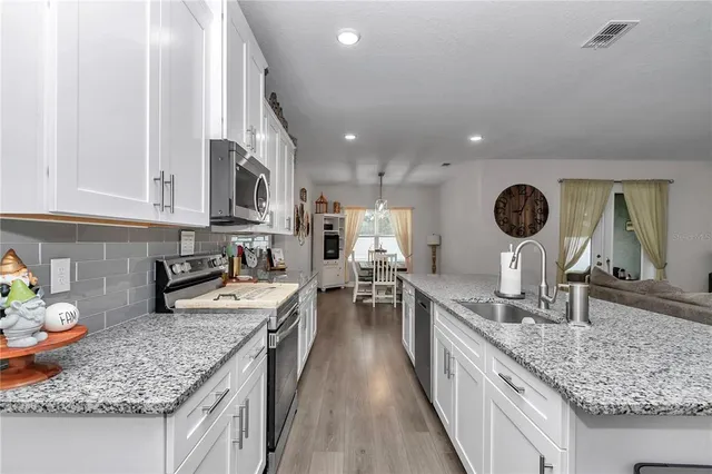 a kitchen with a sink dishwasher stove and white cabinets with wooden floor