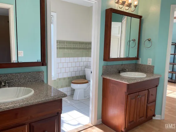 a bathroom with a granite countertop sink a toilet a mirror and window