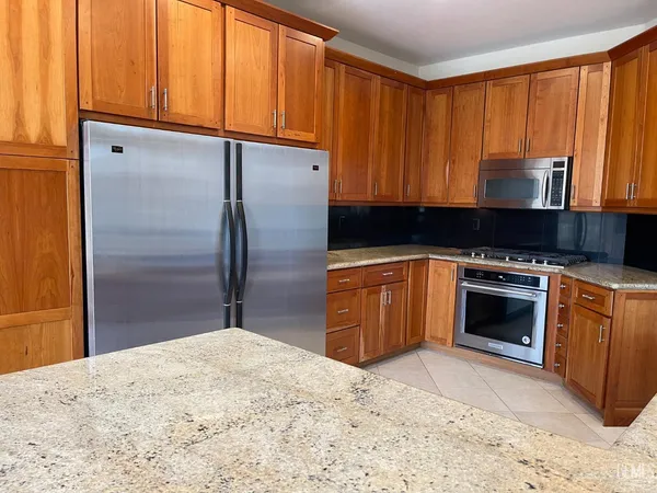 a kitchen with stainless steel appliances kitchen island granite countertop a refrigerator and a sink