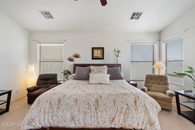 an empty room with chandelier fan and windows