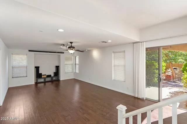 an empty room with windows and ceiling fan
