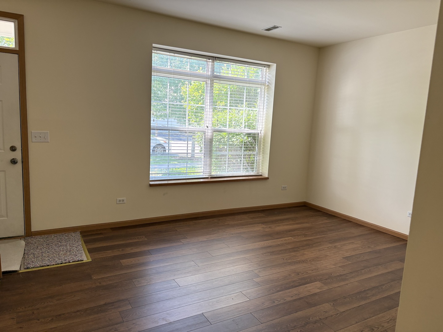 7207 Bradley Drive Plainfield, IL 60586 - Photo 2 of 12 an empty room with wooden floor and windows