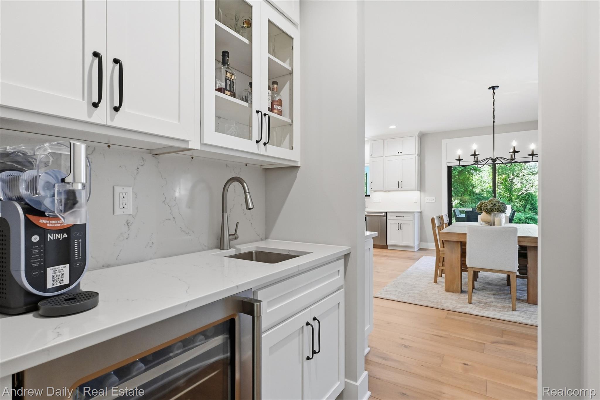 4661 Spears Road Pinckney, MI 48169 - Photo 25 of 56 Wet bar featuring white shaker cabinetry, glass-front upper cabinets, light-toned countertops with a matching backsplash, and an undermount sink with a gooseneck faucet