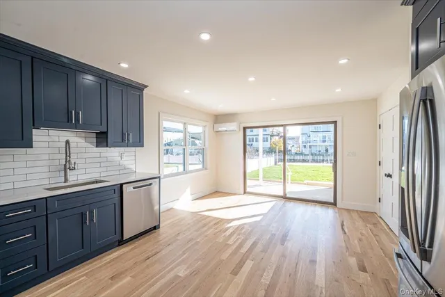 a kitchen with stainless steel appliances granite countertop wooden cabinets a refrigerator a sink a stove a microwave and wooden floors