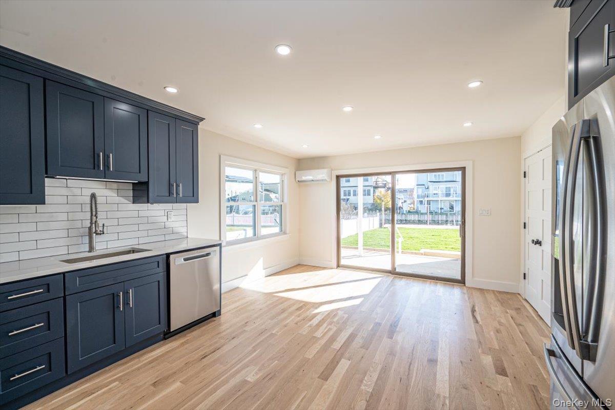 55 Alhambra Road Massapequa, NY 11758 - Photo 8 of 38 a large kitchen with stainless steel appliances granite countertop a refrigerator a sink dishwasher a stove and white countertops with wooden floor