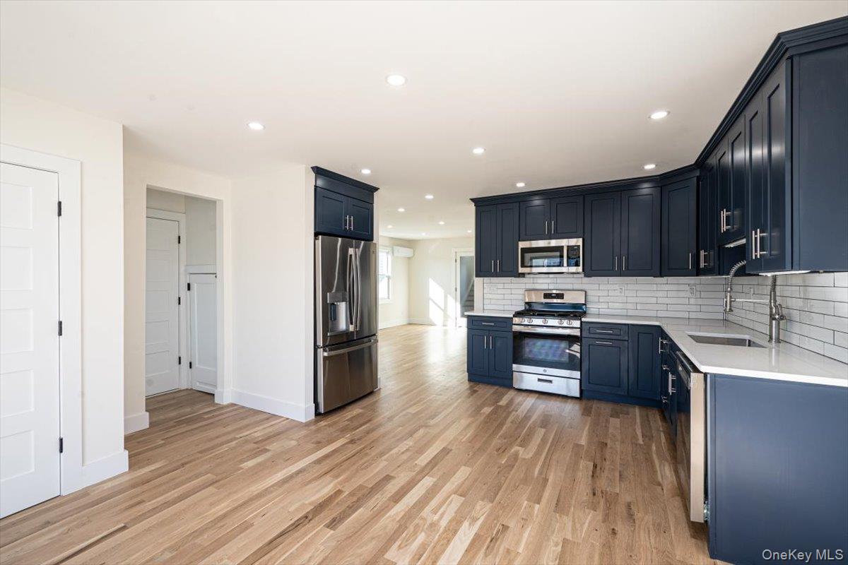 55 Alhambra Road Massapequa, NY 11758 - Photo 9 of 38 a kitchen with stainless steel appliances granite countertop wooden cabinets a refrigerator a sink a stove a microwave and wooden floors