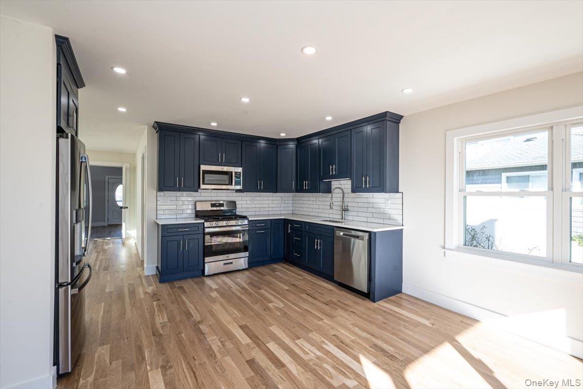 55 Alhambra Road Massapequa, NY 11758 - Photo 10 of 38 a kitchen with stainless steel appliances granite countertop a refrigerator a stove top oven a sink dishwasher and wooden cabinets with wooden floor