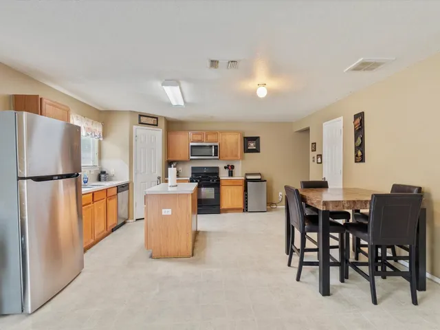 a kitchen with stainless steel appliances a refrigerator a stove a dining table and chairs