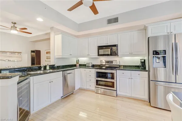 a kitchen with granite countertop a refrigerator stove and sink