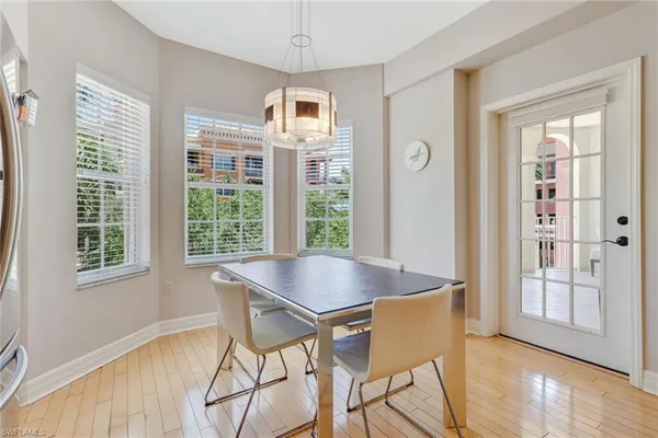 a dining room with wooden floor a chandelier a glass table and chairs