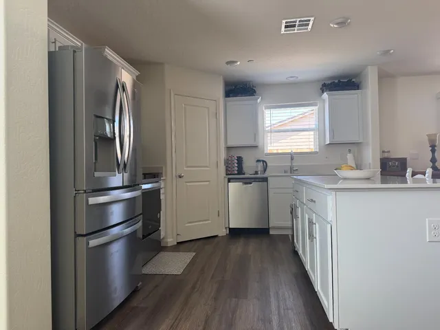a kitchen with a refrigerator a sink and dishwasher with wooden floor