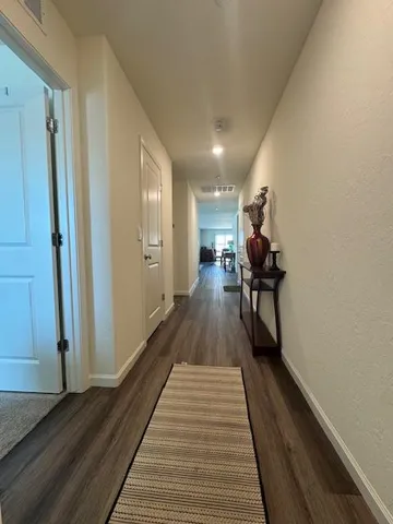 a view of a hallway with wooden floor and furniture