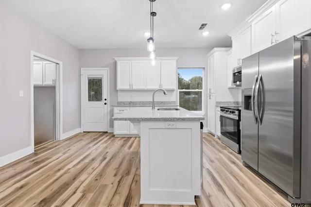 a kitchen with a refrigerator sink and cabinets