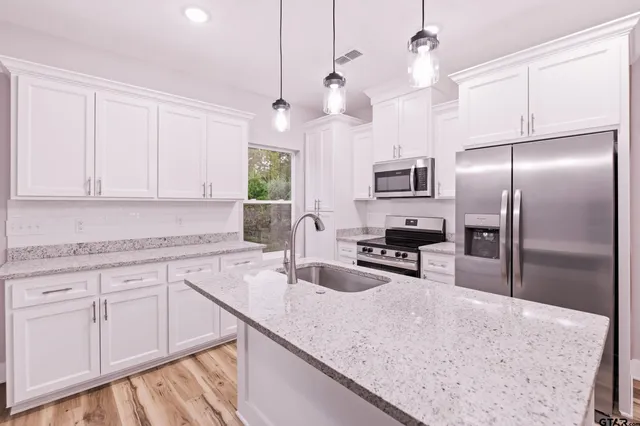 a kitchen with granite countertop a sink a counter top space appliances and cabinets